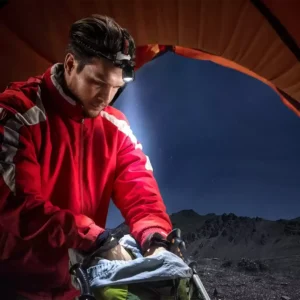 ورزشکار در حال روشن کردن چراغ پیشانی برای حفظ ایمنی در ورزش پاییزی هنگام تاریک شدن هوا